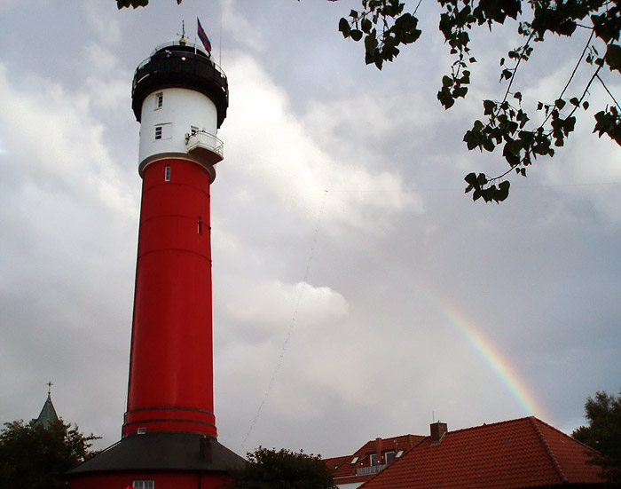 Alter Leuchtturm mit Regenbogen und Funkantennen